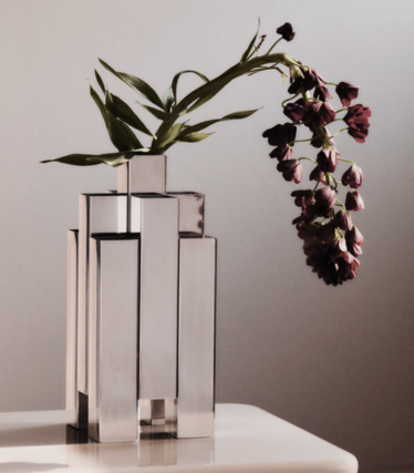 Skulpturale Vase aus poliertem Edelstahl von Ferm Living mit dunkelroten Blüten