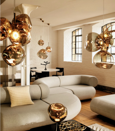 Goldfarbene Melt-Pendelleuchten über einem hellen Sofa in einem Loft mit Sprossenfenstern.